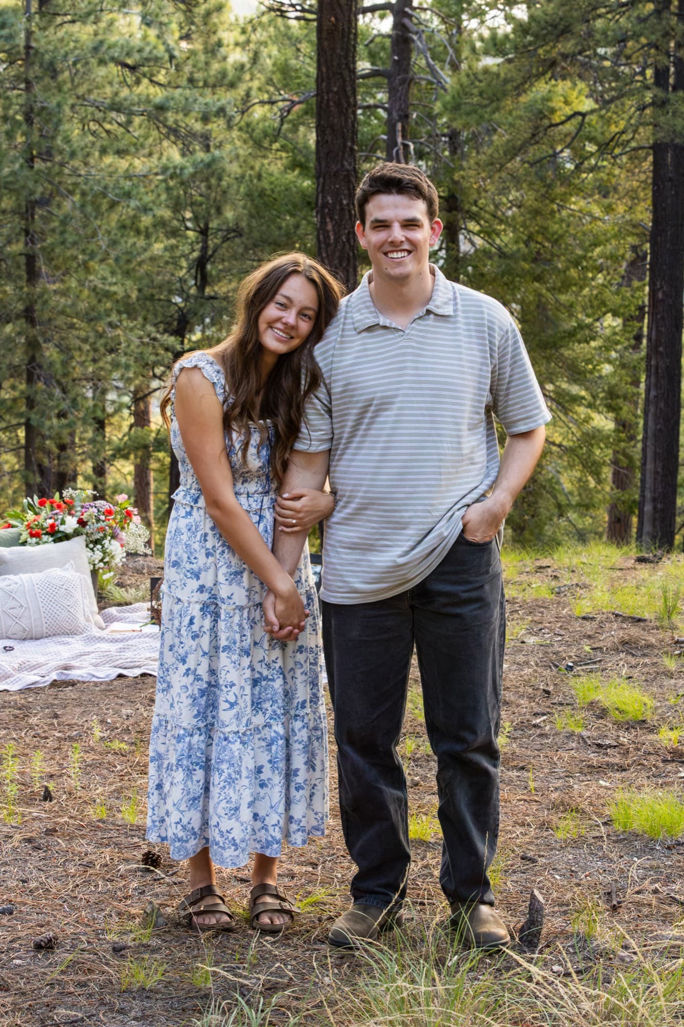 HannahMarie and Trevor standing together among the trees.